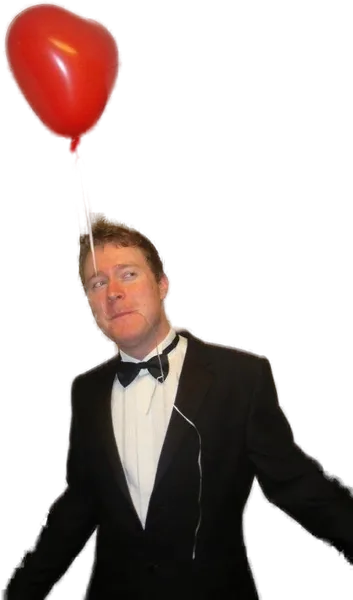 A young James in a tuxedo, holding a red heart-shaped balloon